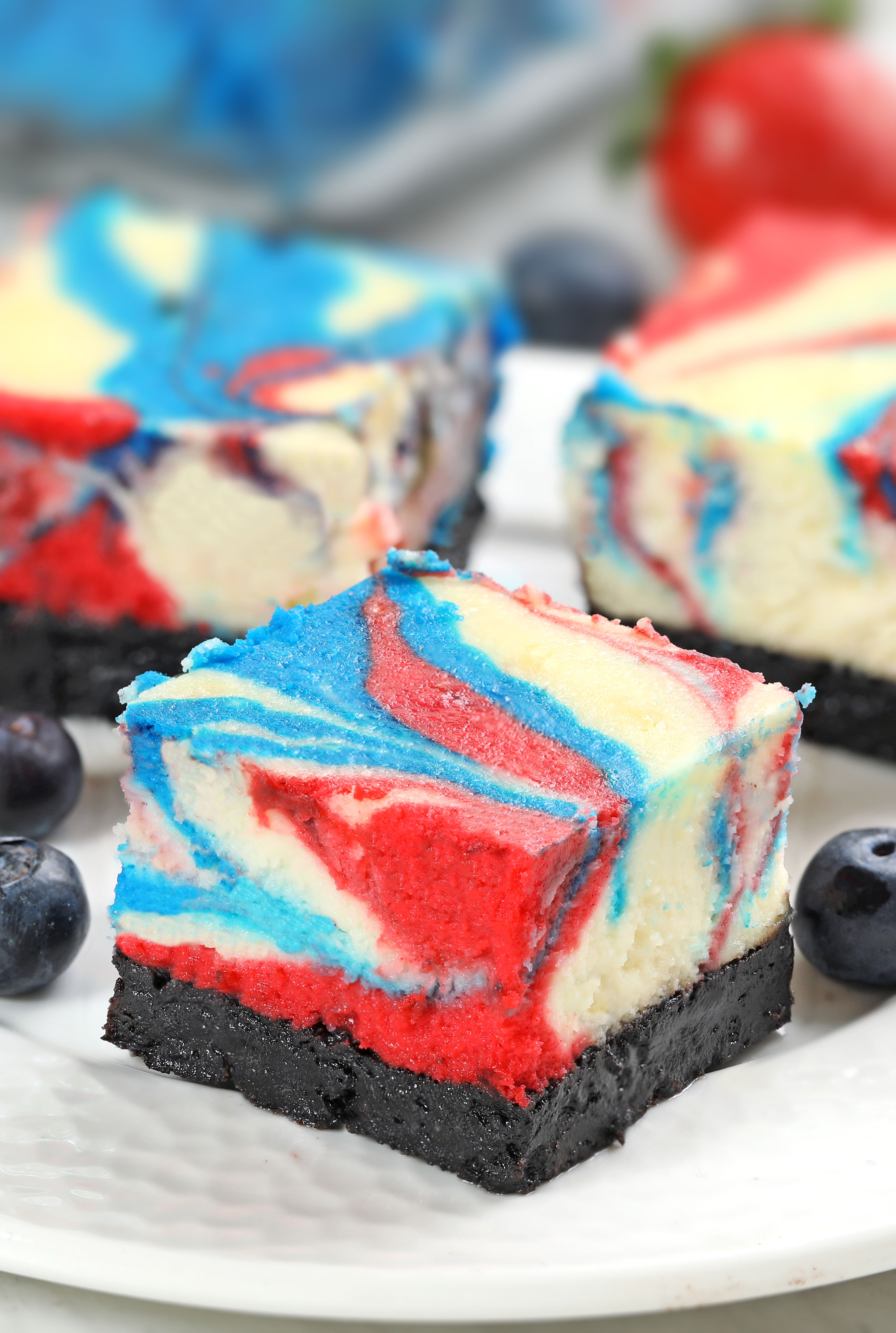 Celebrate 4th of July with these red, white & blue cheesecake swirled bars! Creamy vanilla cheesecake with an Oreo crust, swirled with bold patriotic colors and baked to perfection in a water bath.