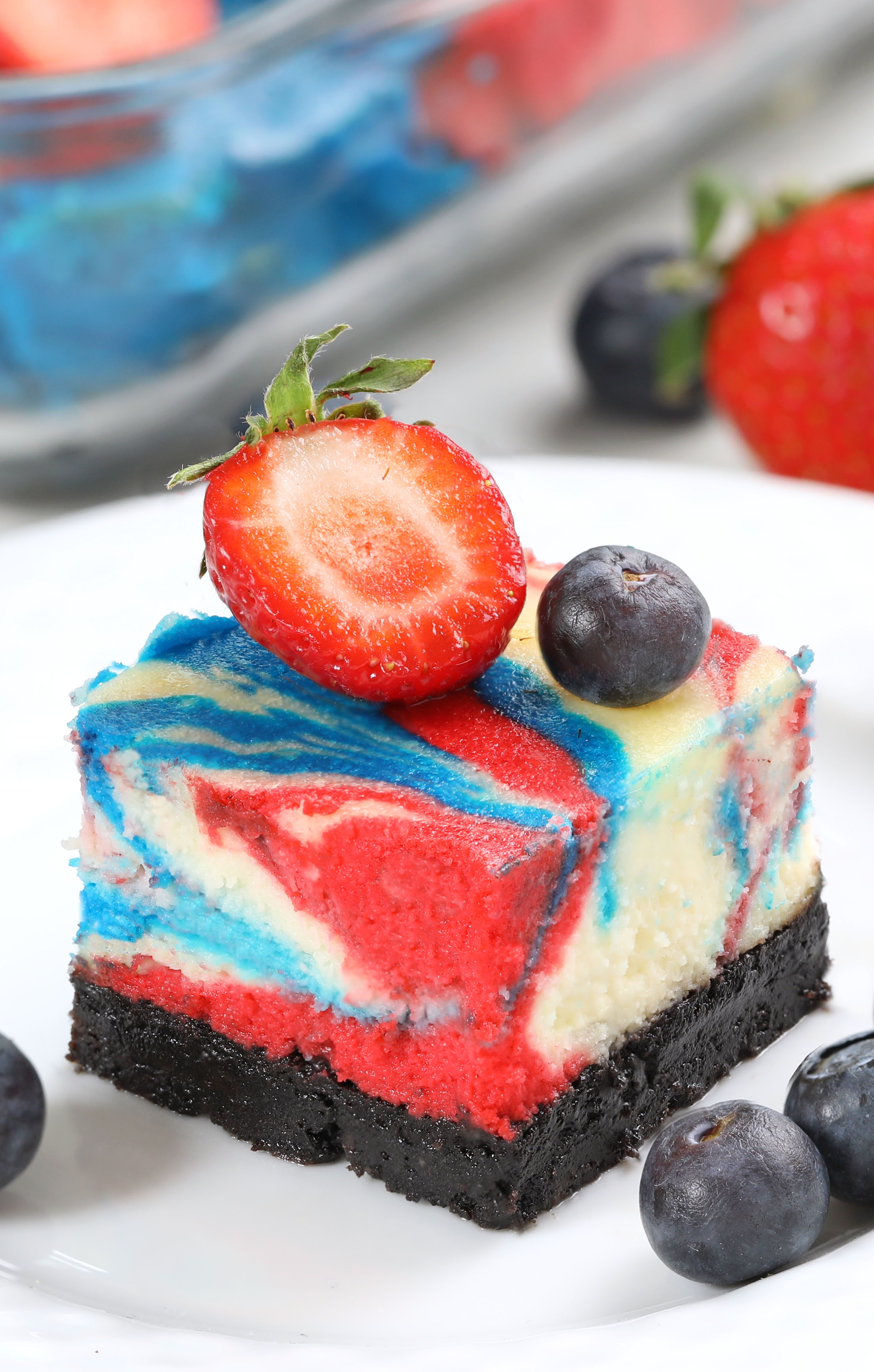 Celebrate 4th of July with these red, white & blue cheesecake swirled bars! Creamy vanilla cheesecake with an Oreo crust, swirled with bold patriotic colors and baked to perfection in a water bath.