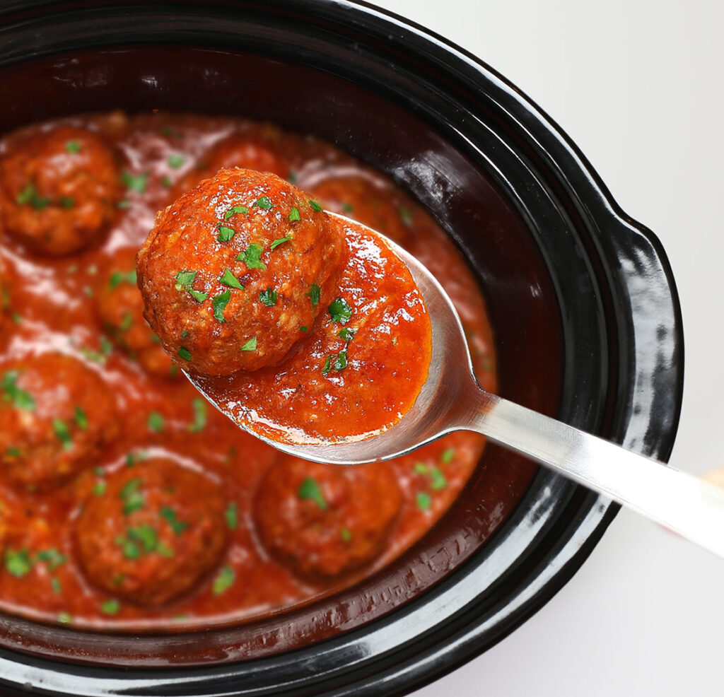 Close up of tender Italian meatballs in red sauce in a slow cooker, easy crock pot meatball dinner.