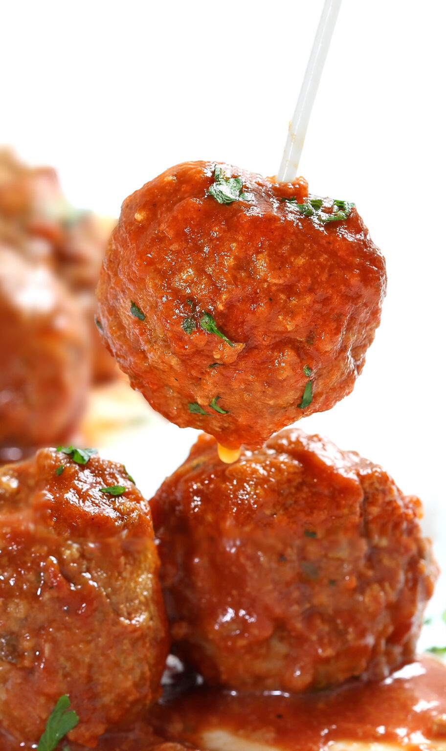 Single Italian meatball on a toothpick dipped in tomato sauce, served as an easy crock pot meatball appetizer